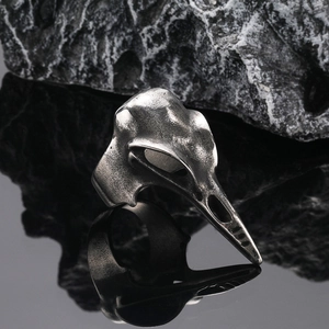 Bague crâne de pivert gothique en argent mat sur un fond de roche sombre texturée