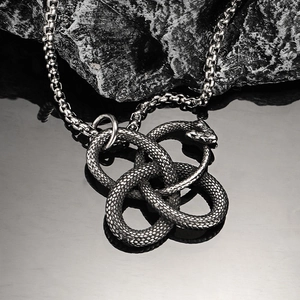 Close-up of vintage stainless steel Ouroboros snake pendant with Celtic knot details
