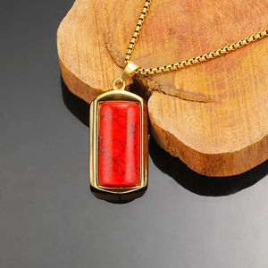 Detailopname van een rechthoekige rode steen hanger aan een gouden box-ketting