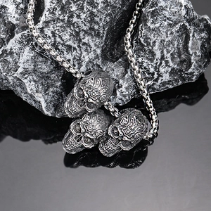 Pendentif trois crânes en acier inoxydable style rétro punk sur fond de roche noire