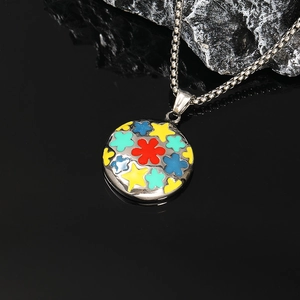 Détail macro du pendentif étoile fleur en émail sur une chaîne à maillons carrés