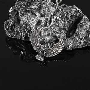 Detailed macro shot of an eagle pendant with intricate feather textures on dark rock