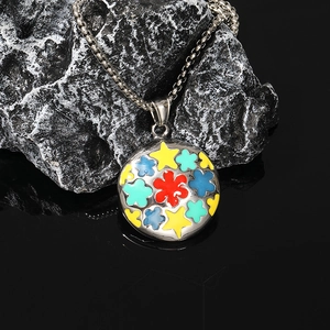 Pendentif fleur et étoile en émail coloré sur roche naturelle sombre avec réflexion