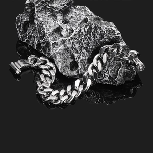 Dettaglio macro del bracciale a maglie cubane argento pesante con fibbia su pietra scura