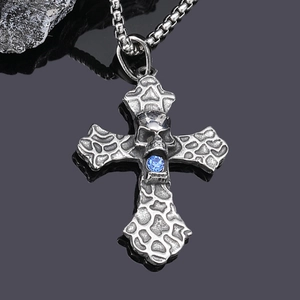 Macro detail of gothic skull cross pendant with blue crystal on vintage steel chain