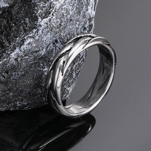 Vintage braided silver titanium steel ring with punk style texture on dark stone surface