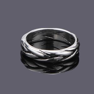 Macro shot of silver titanium steel ring with vintage braided cable texture and reflection