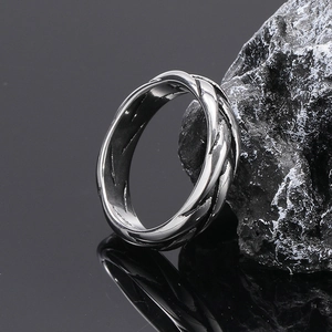 Polished silver braided stainless steel ring for men on a dark rock background