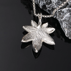 Macro detail of silver maple leaf pendant with realistic vein texture on rugged stone