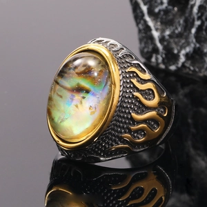 Close-up of a men's punk ring featuring golden flame patterns and an abalone stone