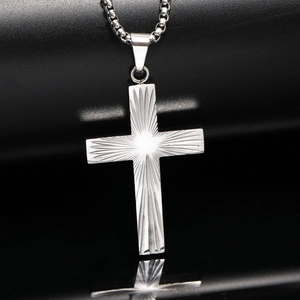 Vue macro du pendentif croix en acier inoxydable argenté avec texture rayonnante