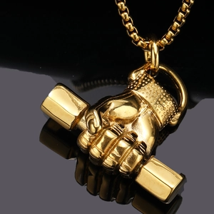 Vue macro du collier pendentif poing haltère doré sur surface noire réfléchissante