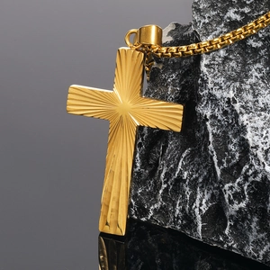 Gros plan détaillé du pendentif croix dorée en acier inoxydable avec texture rayonnante