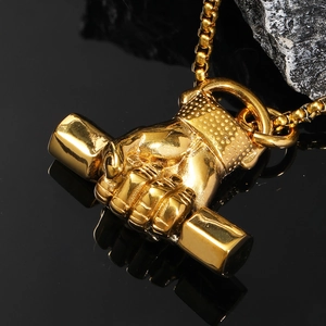 Macro d'un pendentif haltère poing plaqué or avec chaîne box sur fond de roche noire
