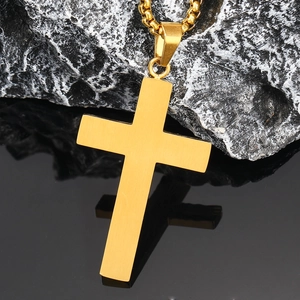 Vue macro d'un pendentif croix en titane doré avec finition mate brossée sur pierre noire