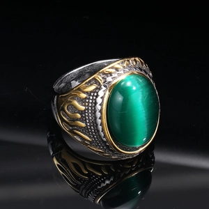 Detailed close-up of a vintage punk ring with green cat eye stone and gold flame relief