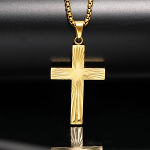 Gros plan du pendentif croix dorée avec texture rayonnante et chaîne à mailles carrées