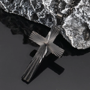 Détail macro du pendentif croix en acier noir avec texture radiale sur une pierre
