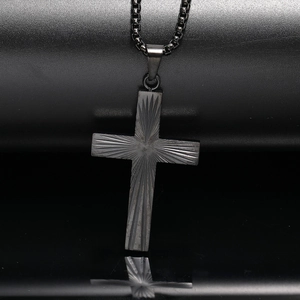 Vue macro d'un pendentif croix en acier noir avec gravure radiale texturée