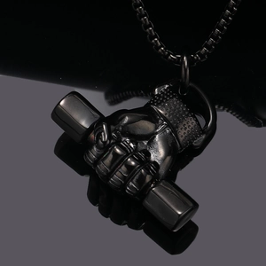 Gros plan d'un pendentif fitness en métal gris fusil montrant un poing serrant un haltère