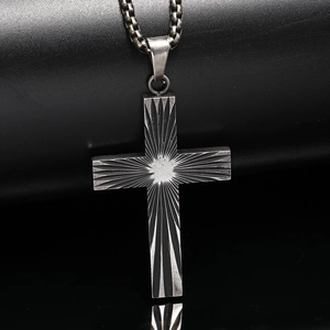 Vue macro du pendentif croix rétro en acier titane avec texture radiale et chaîne box