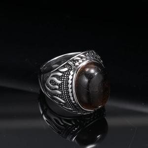 Macro shot of vintage titanium steel ring featuring flame patterns and a large brown gemstone