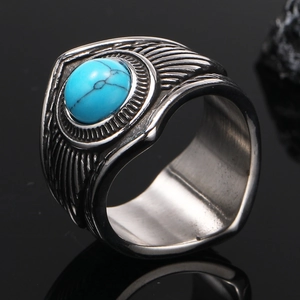 Détail macro d'une bague vintage en acier avec plumes gravées et incrustation turquoise
