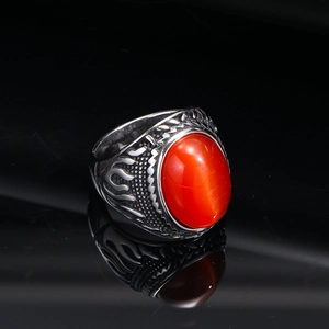 Macro shot of punk flame-textured ring with a cat-eye red gemstone and silver-black finish