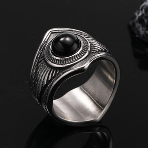Gros plan d'une bague en acier titane vintage avec plume et pierre noire sertie