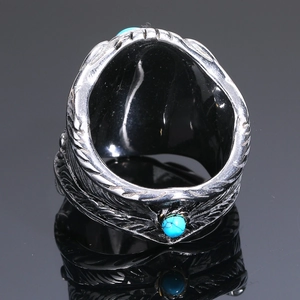 Vista macro de anillo de acero de titanio plateado con turquesa azul y grabados de plumas