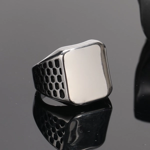 Macro shot of silver men's signet ring with honeycomb cutout texture and flat rectangular face
