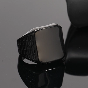 Macro shot of black titanium signet ring with square face and honeycomb side texture