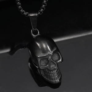 Macro shot of matte black punk skull pendant with square chain links on mirror