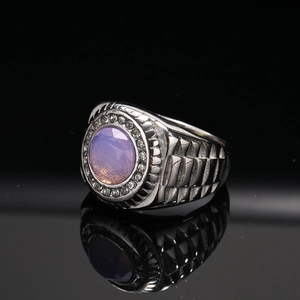 Macro-opname van een titanium ring met paarse ovale steen en band met rupsbandtextuur