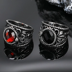 Vintage gothic titanium steel rings with red and black gemstones on a reflective surface