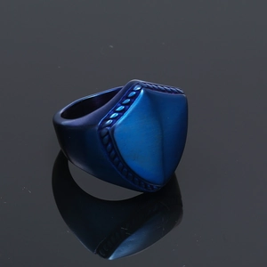 Detailed close-up of blue shield-shaped titanium steel ring with textured rope edge
