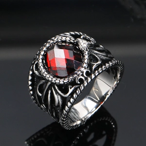 Macro shot of vintage steel ring featuring a red faceted gemstone and snake relief texture