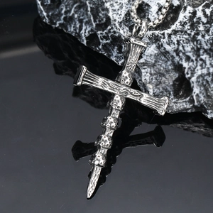 Gothic skull cross pendant in vintage silver stainless steel on a black reflective surface