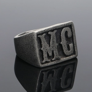 Makroaufnahme von Retro-Siegelring aus Edelstahl mit geprägtem MC-Buchstabendetail