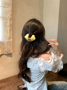 Elegante pinza per capelli con rosa in tessuto giallo 3D su modella con semiraccolto