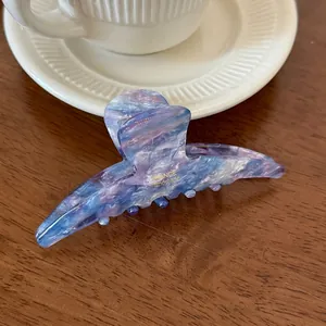 Detailed close-up of blue marble acetate hair claw clip with gold handmade engraving