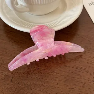 Detail of pink marble acetate hair claw clip with gold France Handmade logo on wood table