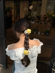 Vista dettagliata di un fermaglio per capelli e elastico con fiore di rosa in raso giallo