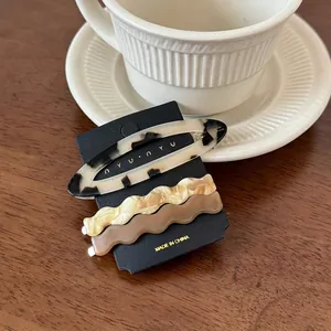 Detailed view of three acetate hair clips featuring oval and wave shapes on a card