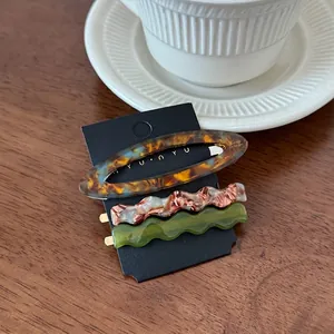 Three-piece acetate hair clip set featuring tortoiseshell and marble patterns on wood