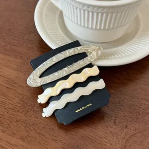 Three-piece acetate hair clip set with oval marble and wave designs on wood surface