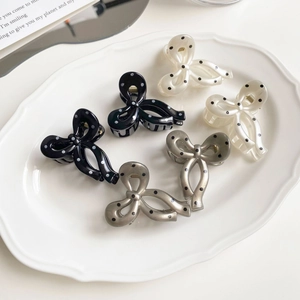 Five pieces of polka dot bow hair clips in black, white, and grey on a decorative tray