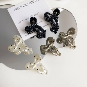 Detailed view of polka dot bow hair claws in black, white and grey on a mirror