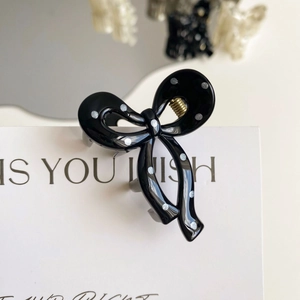 Close-up of black hair claw clip with white polka dots and gold metal spring detail