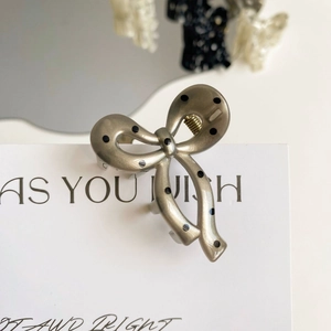 Close-up of alloy bow hair claw with black polka dots and silver-gray matte finish